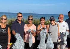 Residents are holding bags of trash collected during a monthly beach cleanup.