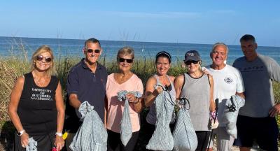 Residents are holding bags of trash collected during a monthly beach cleanup.